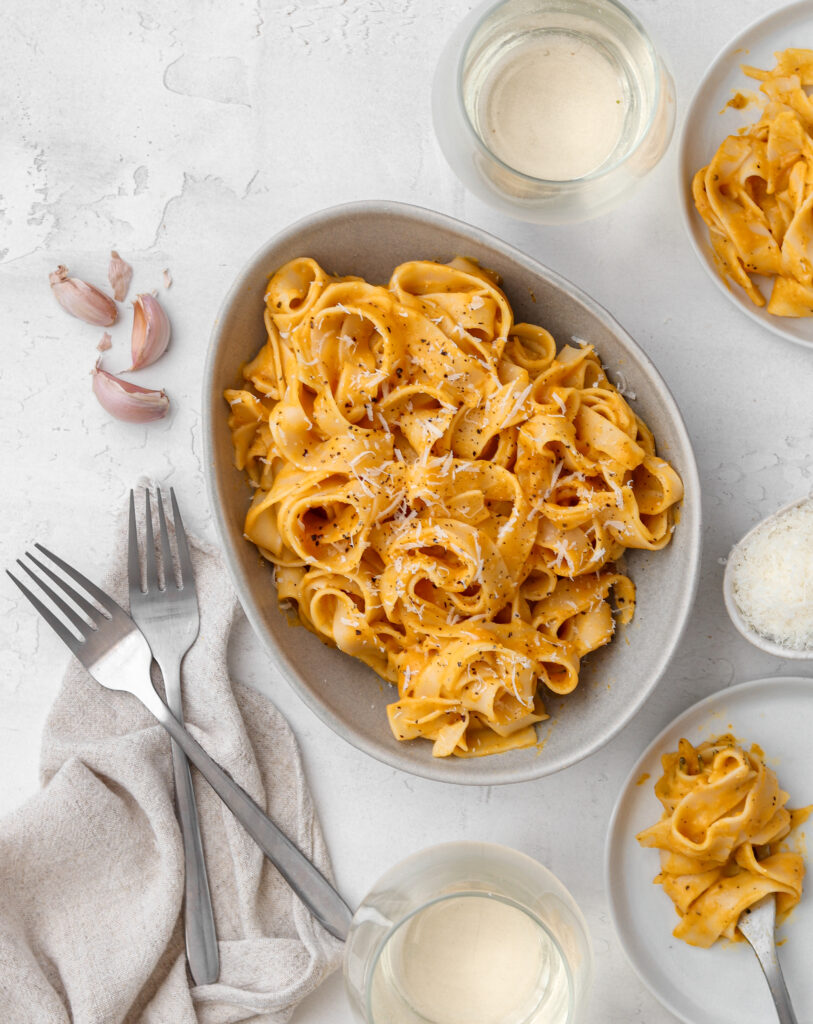 Bowl of pasta with cutlery and wine surrounding it