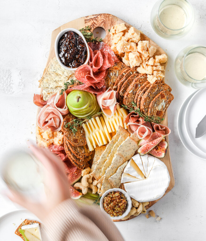 Cheese board with wine glasses and a moving hand out of focus