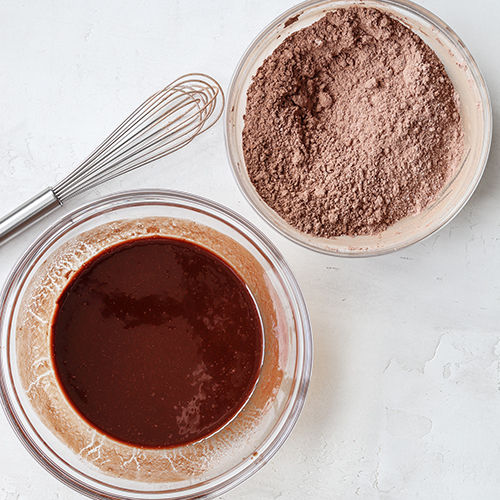 Two bowls of melted chocolate and flour and cocoa