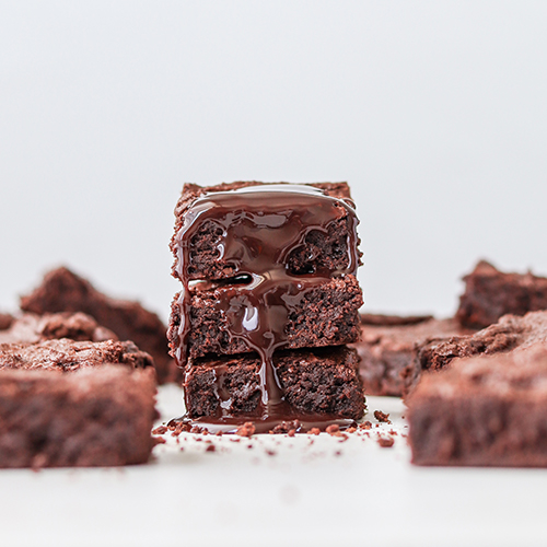 Stack of brownies with chocolate sauce dripping down them