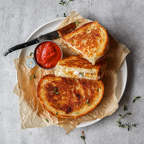 Grilled cheese sandwiches on a plate with marinara sauce