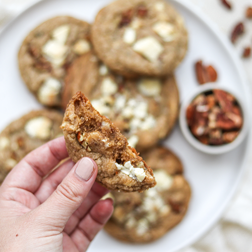 Hand holding a white chocolate pecan cookie