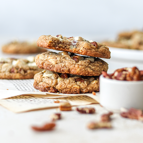 Cookies stacked on each other on pages with pecans in foreground