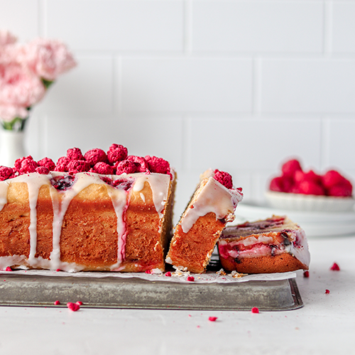 Slices of lemon raspberry loaf cake falling down onto parchment lined tray