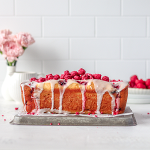 Lemon and raspberry loaf cake sitting on top of metal tray and parchment paper