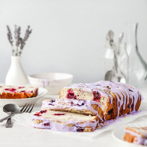 Blackberry loaf cake with a lavender glaze. The cake is sliced and sitting on parchment paper