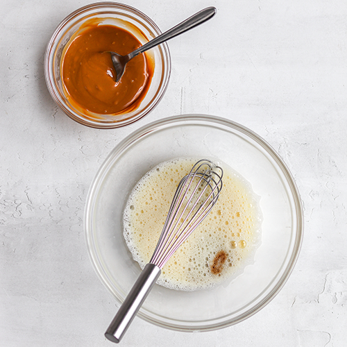 Bowl of whisked eggs with vanilla and a smaller bowl with biscoff spread