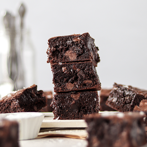 Ultimate fudgy brownies stacked on top of each other with more brownies surrounding it