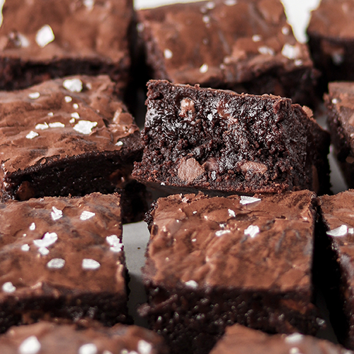 Close up image of brownies showing off the fudgy centre and chocolate chips