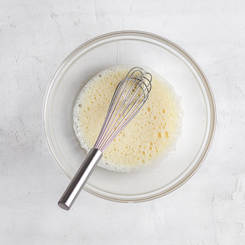 Whisked eggs in a bowl with a whisk in it