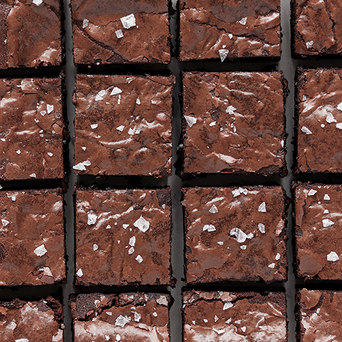 Overhead image of perfectly sliced brownies with flaky salt on top